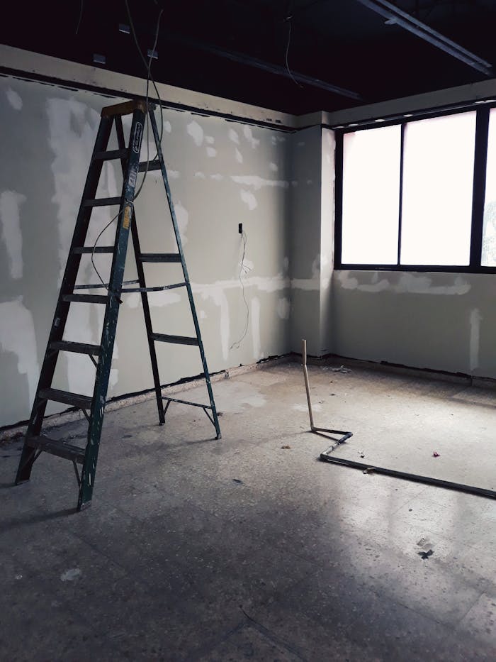 Empty room with ladder and natural light, ideal for renovation or restoration projects.